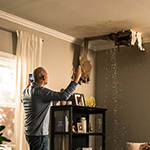 Water leaking from a roof and an individual looking at it.